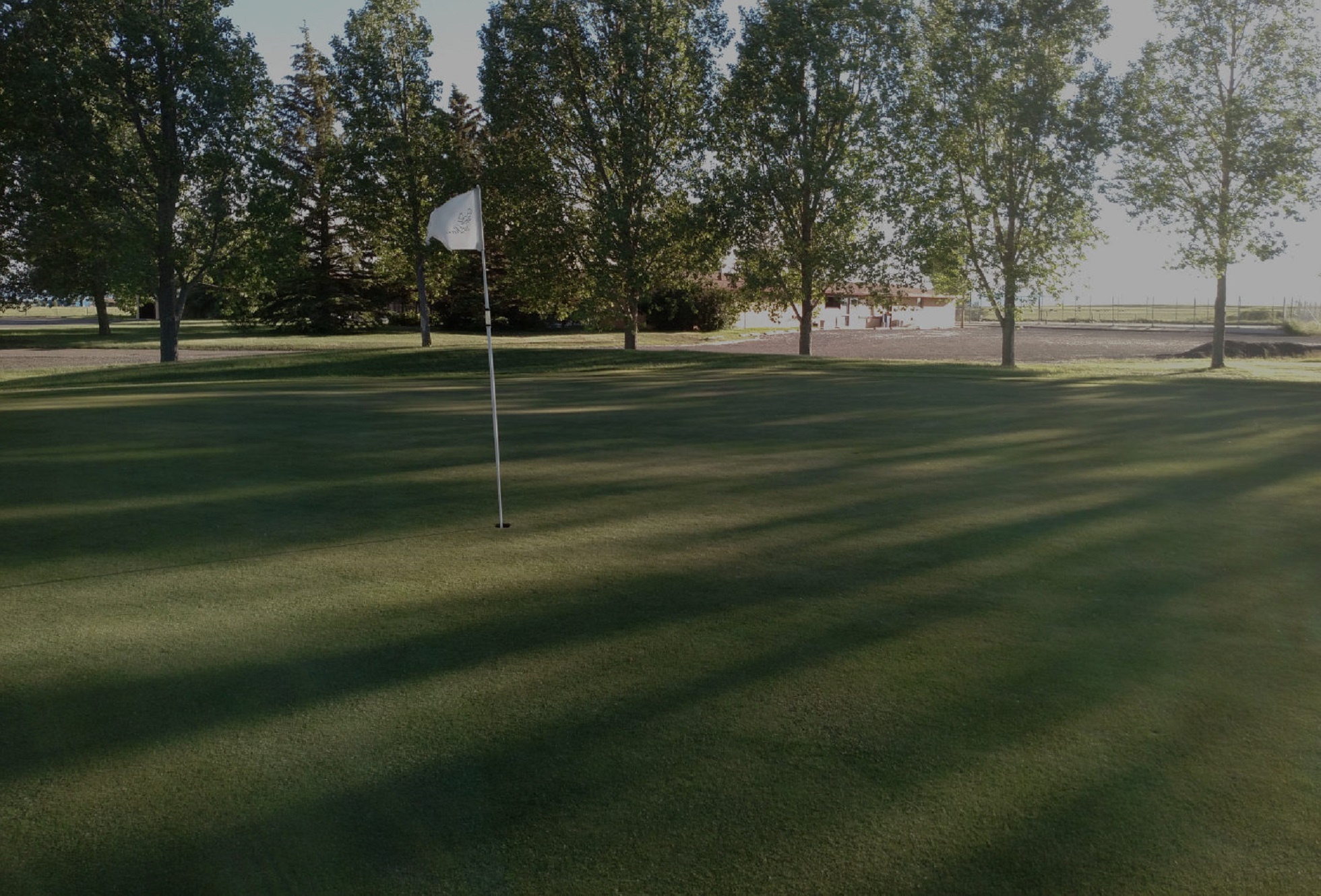 Golf course green with white flag over hole